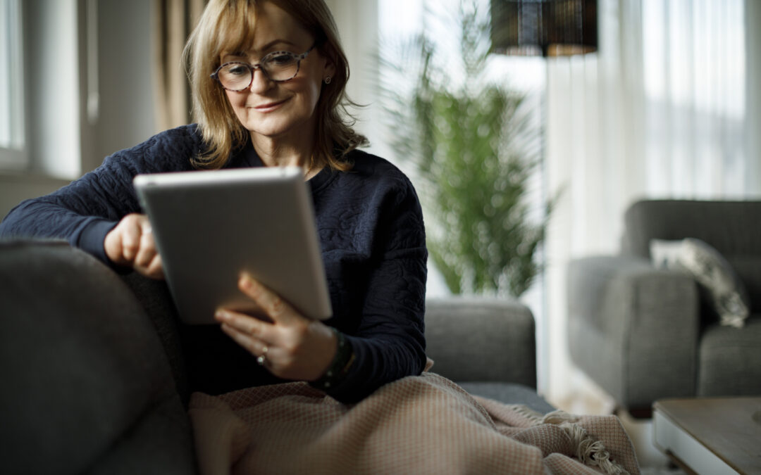 Smiling senior woman using digital tablet at home to understand the differences among the types of retirement communities in DC